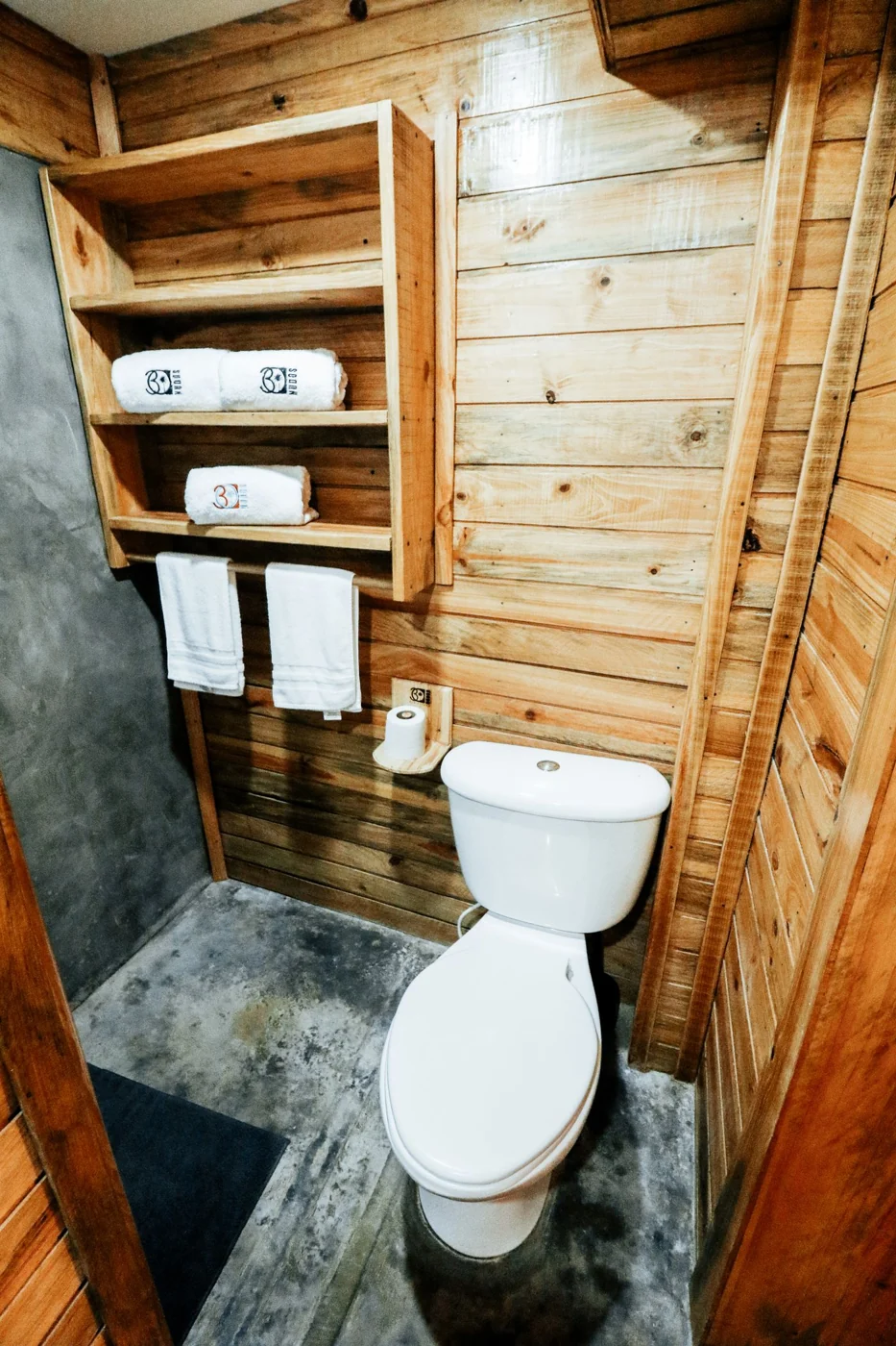 A Brown Wooden Walled Bathroom with Gray Flooring.