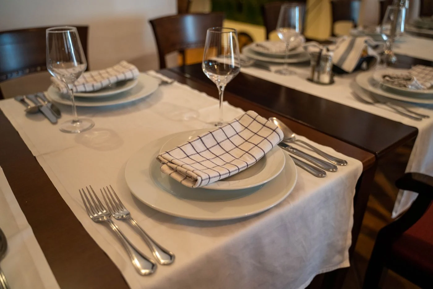 Checked cloth napkins on a table set with cups and plates.
