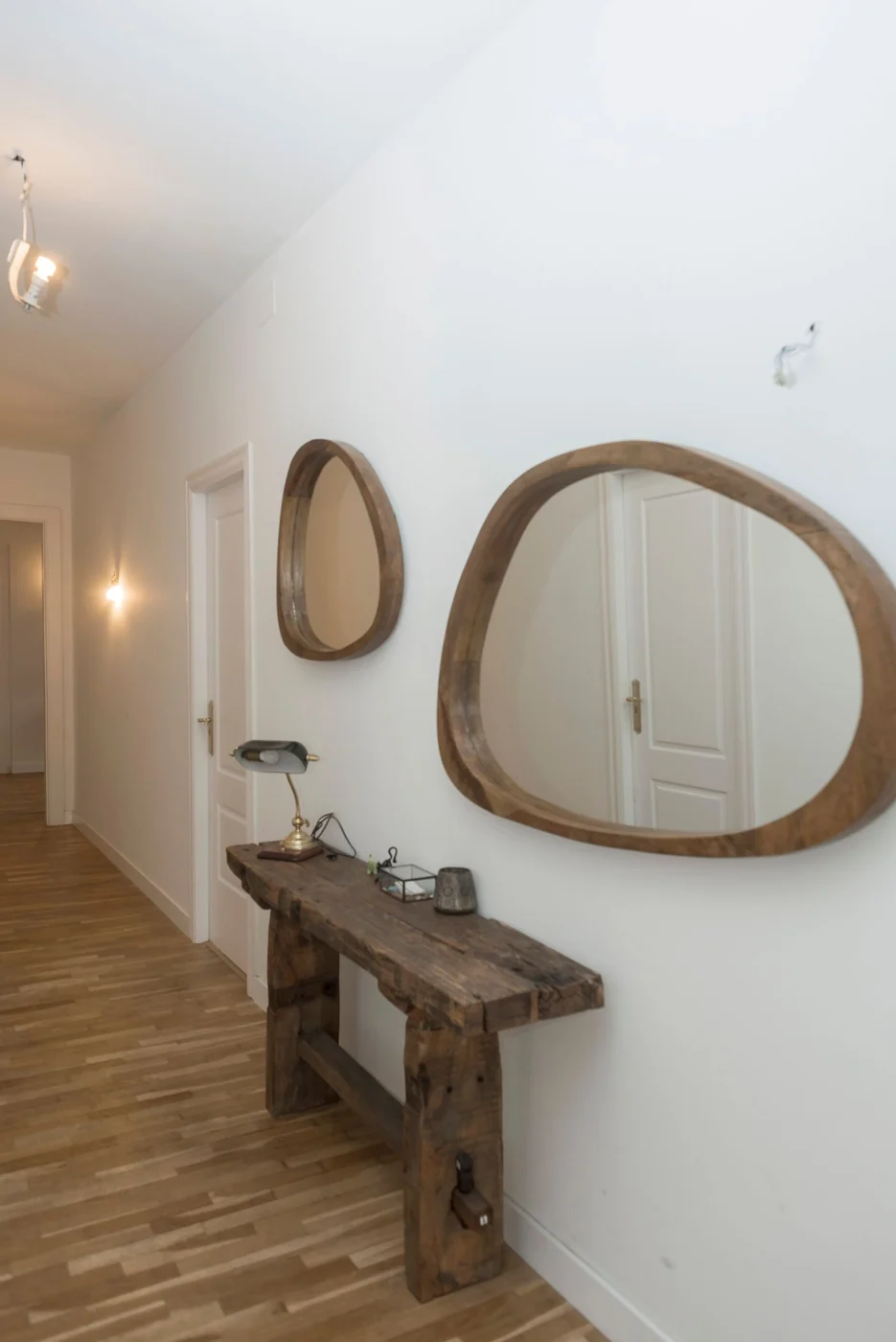 Stylish hallway with wooden mirrors and console table on white walls.