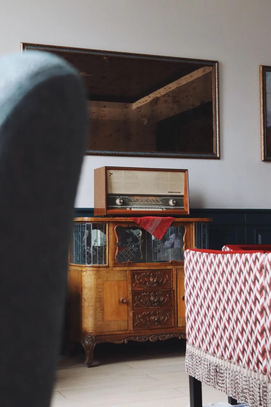 A vintage radio sits on an ornate wooden cabinet, evoking a retro interior design in a cozy room.