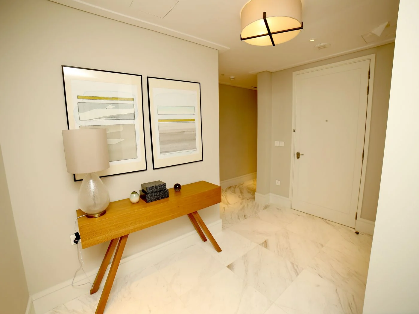 Stylish hallway interior in Dubai featuring modern art and a wooden console with a lamp.