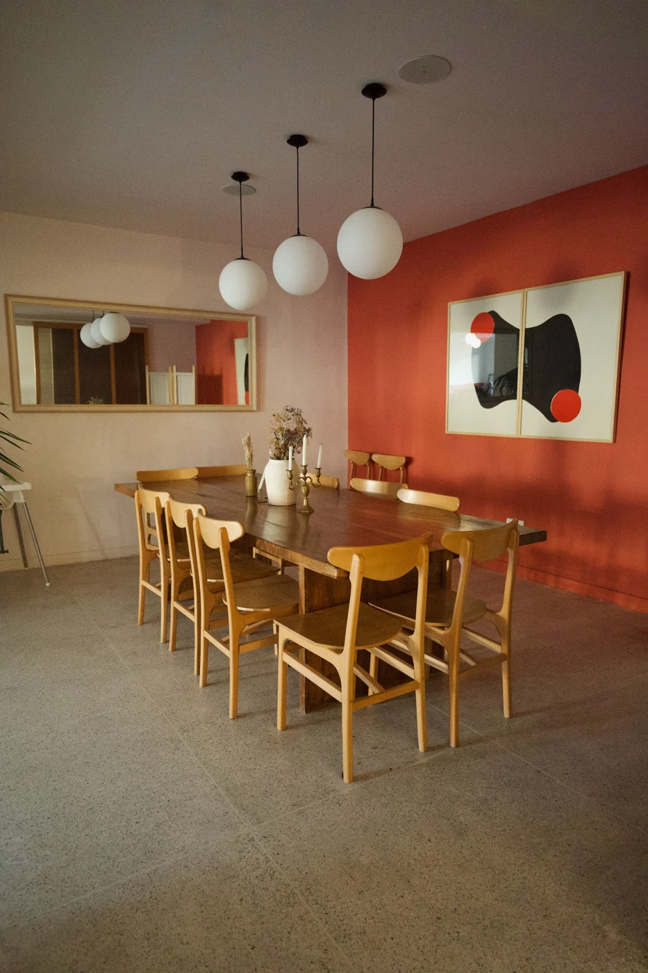 A contemporary dining room with a wooden table, chairs, and pendant lights.