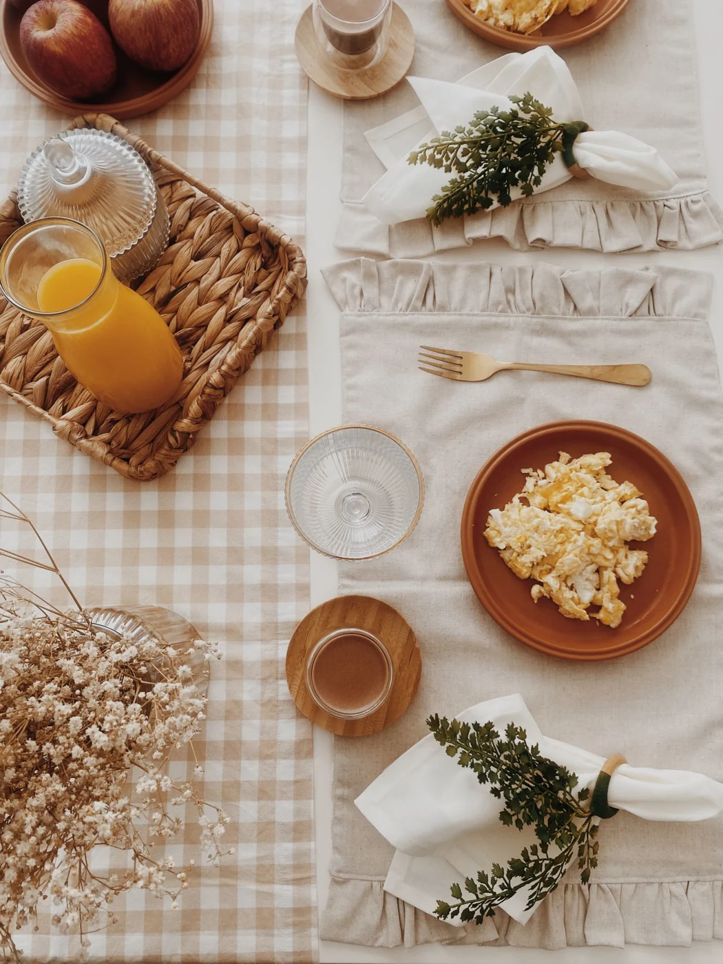 A cozy breakfast setup with scrambled eggs, orange juice, and rustic decor on a checkered tablecloth.