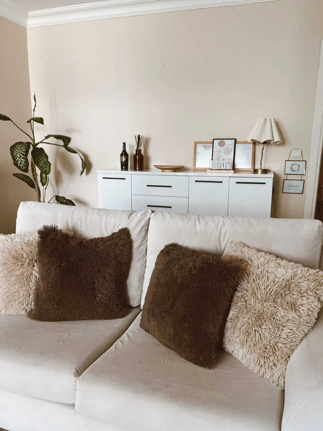 Comfortable beige sofa with fluffy pillows in a modern living room.