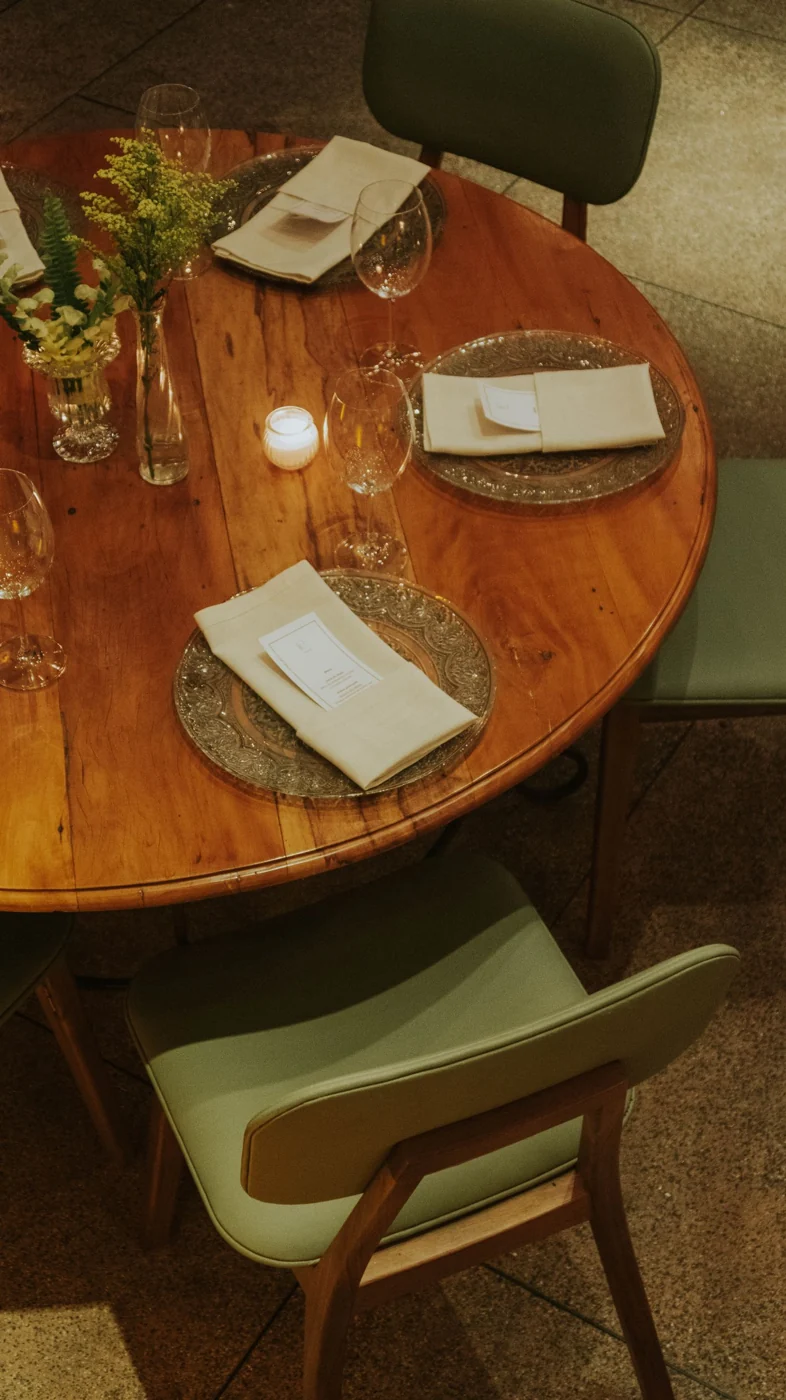 A beautifully arranged round table set for dinner with candles, flowers, and formal place settings.