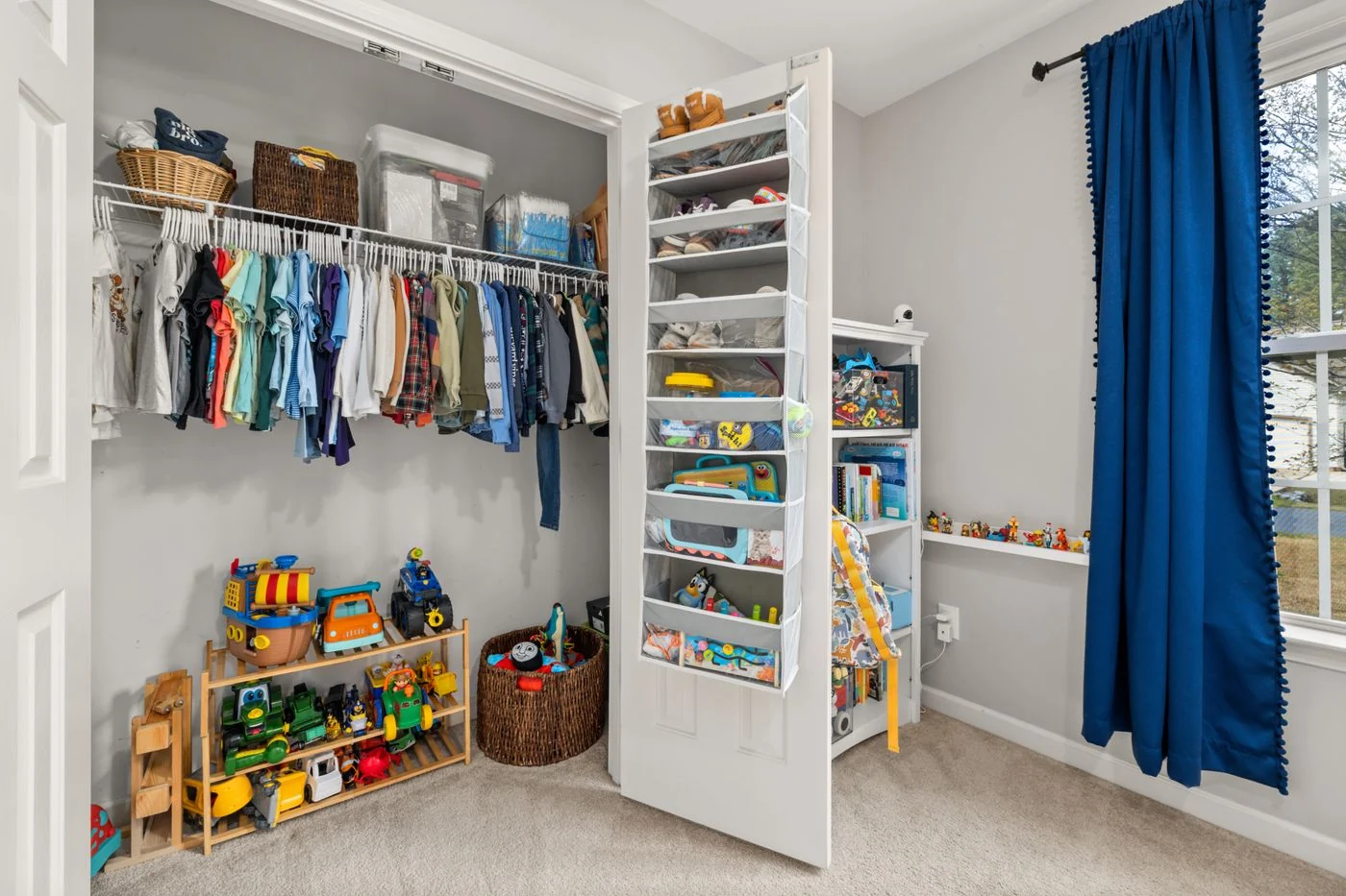 Open shelves and hanging clothes in a child's room.