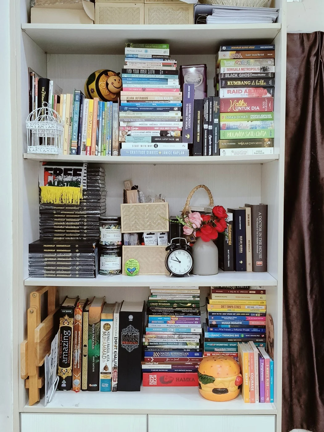 A colorful bookshelf filled with books and decor items in a cozy home setting in Negeri Sembilan, Malaysia.