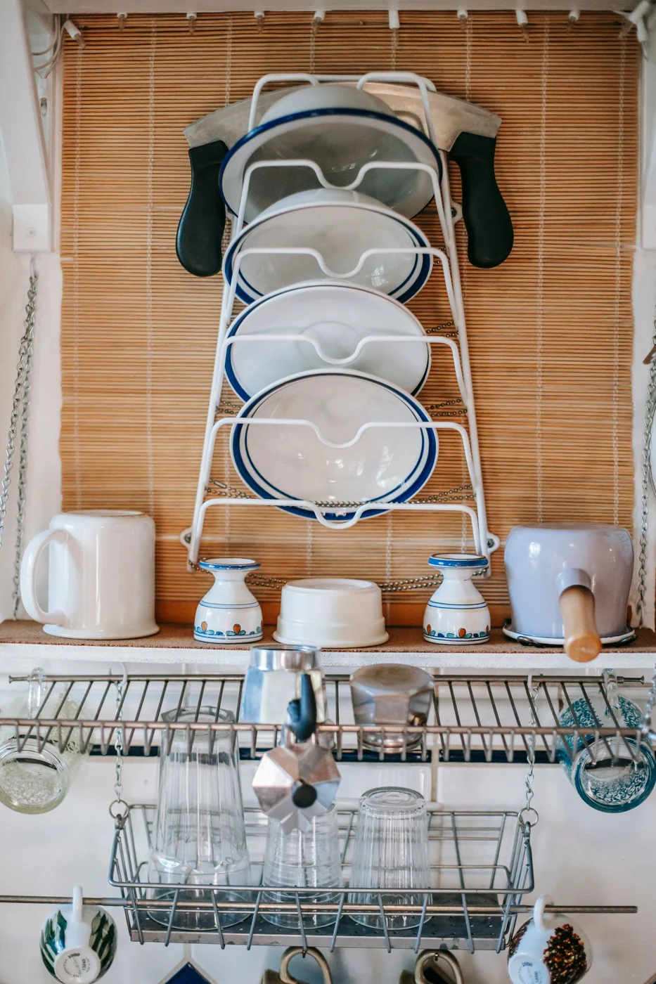Elegant and organized dish rack with plates, cups, and kitchenware in a cozy kitchen setting.