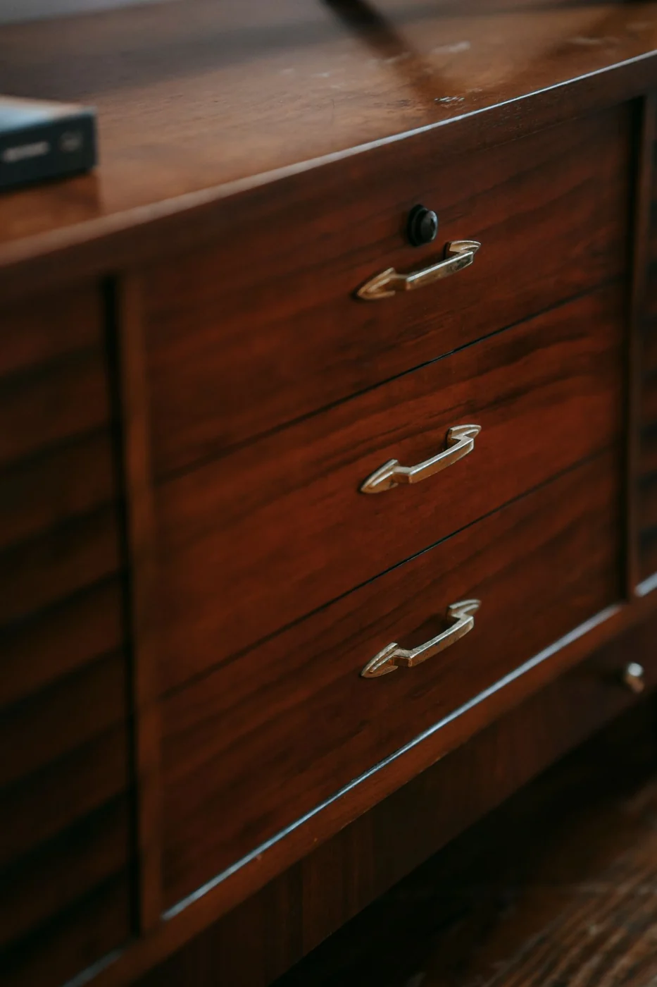 Close-up of a vintage wooden dresser with brass handles in a cozy interior.