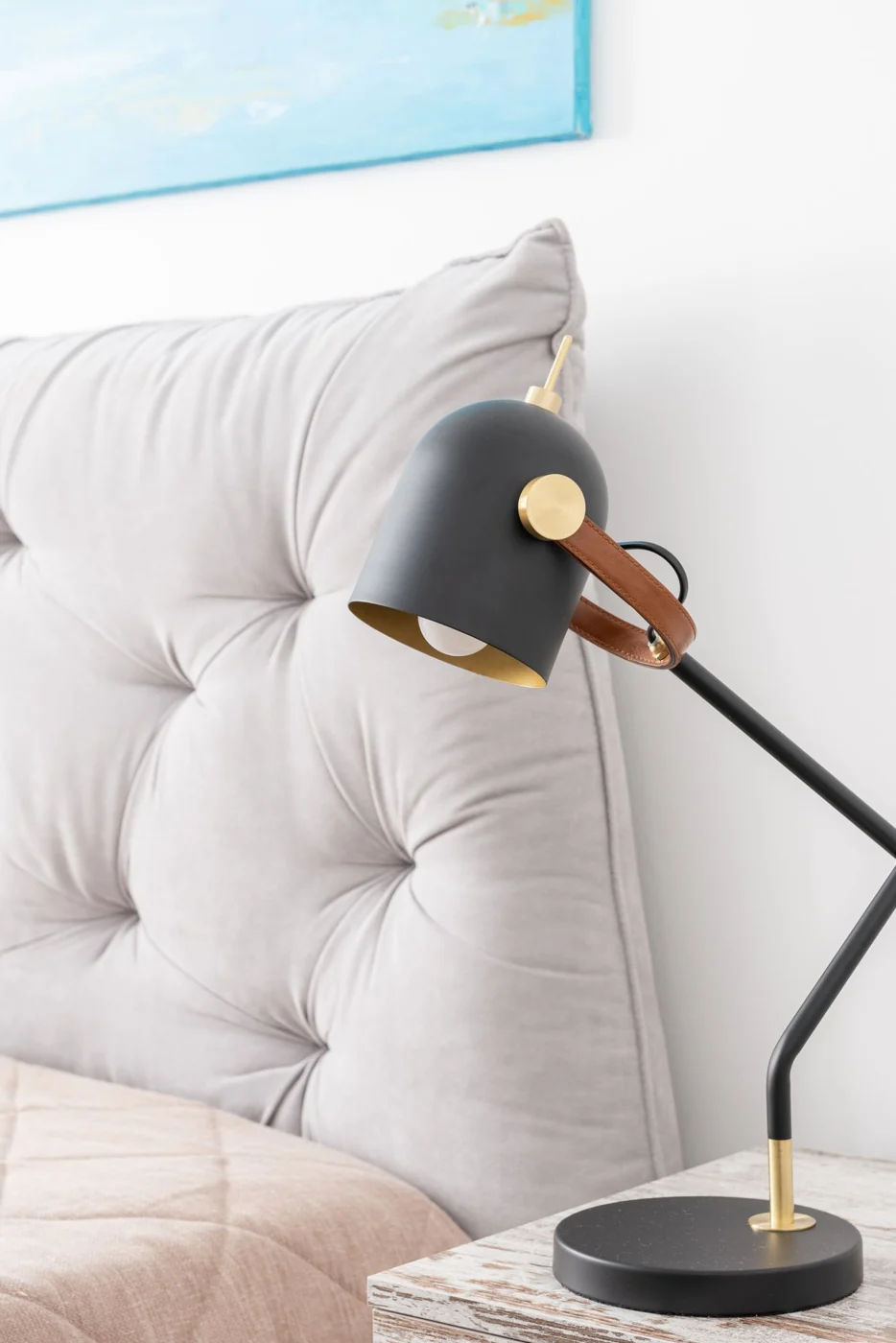 A contemporary bedroom setup featuring a stylish lamp and tufted headboard with soft lighting.