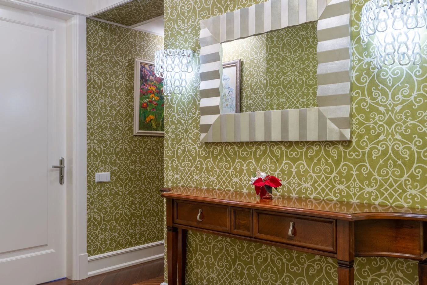 Sophisticated hallway featuring ornate wallpaper, a wooden console, and a striking decorative mirror.