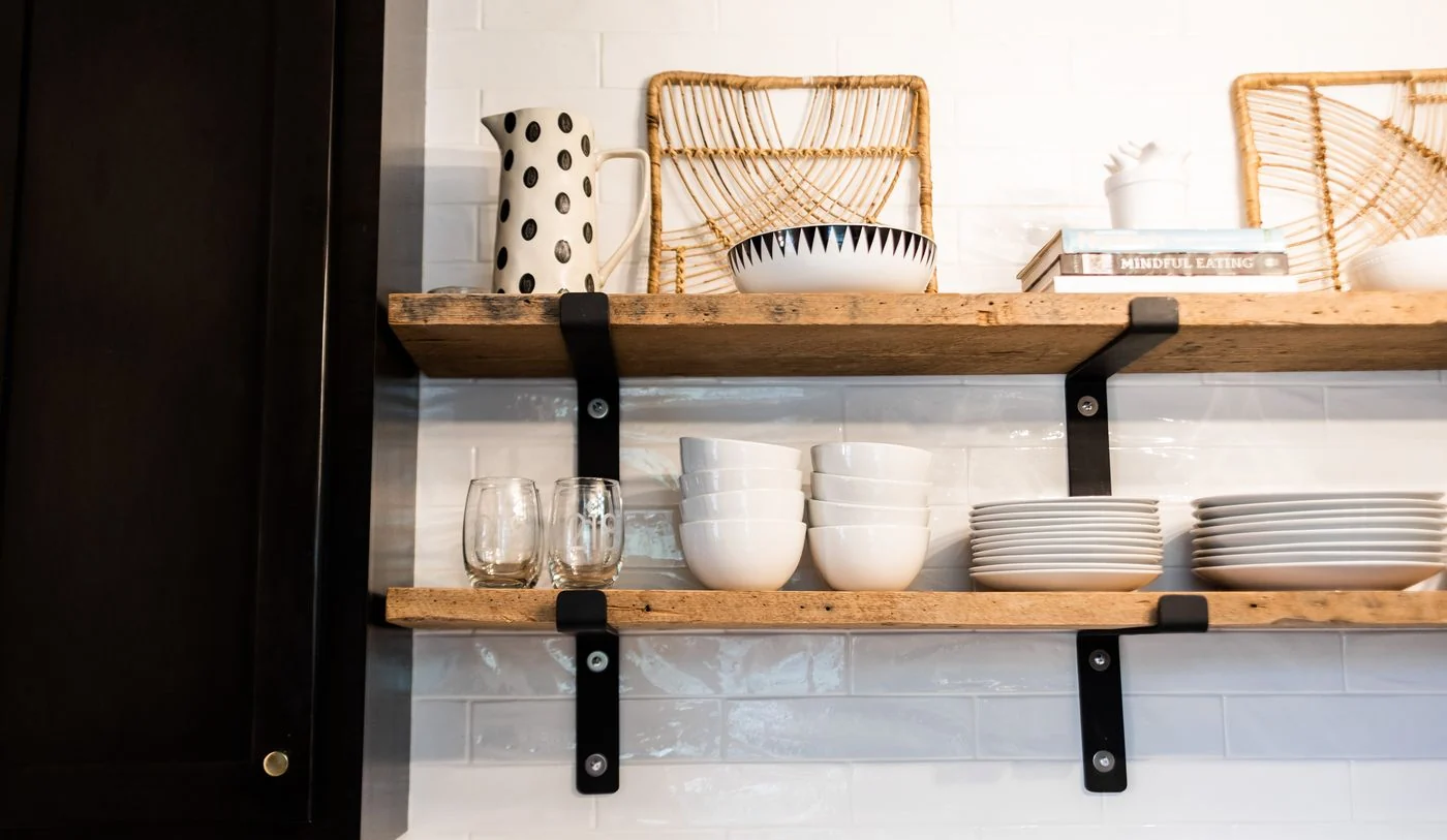 Sleek kitchen shelves featuring ceramic dishes, glassware, and wicker decor.