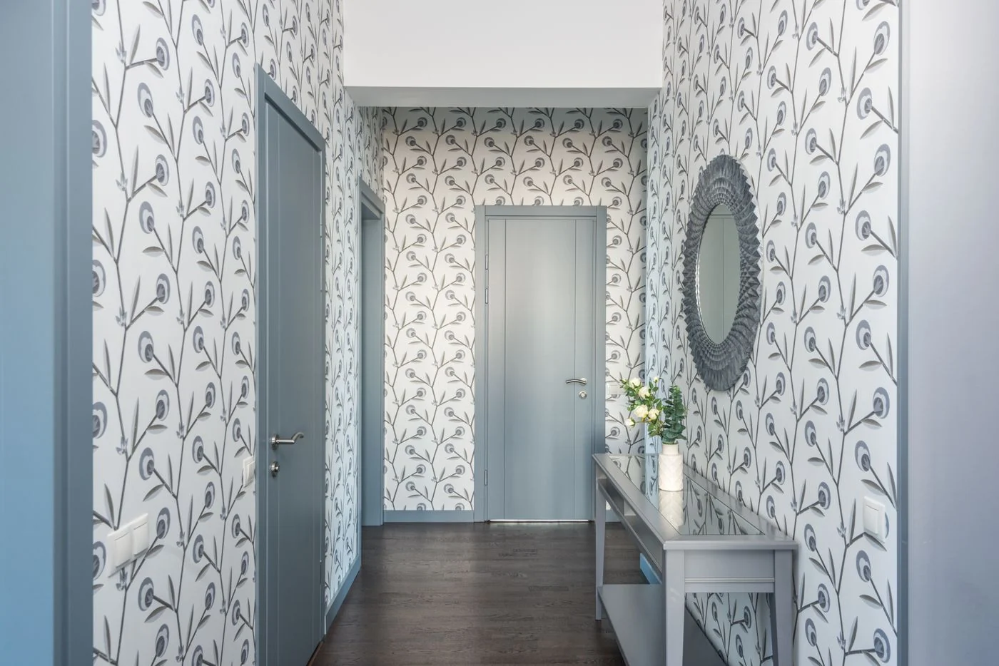 A stylish hallway featuring floral wallpaper, a console table, and a decorative mirror.