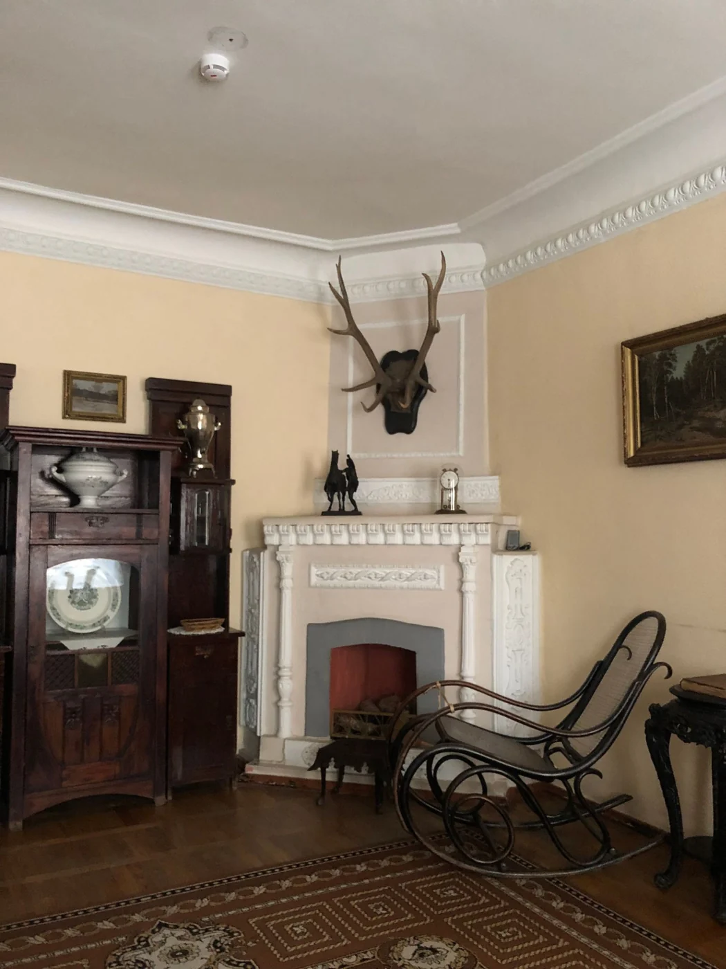 Charming vintage room featuring antique furniture, a fireplace, and decorative antlers.