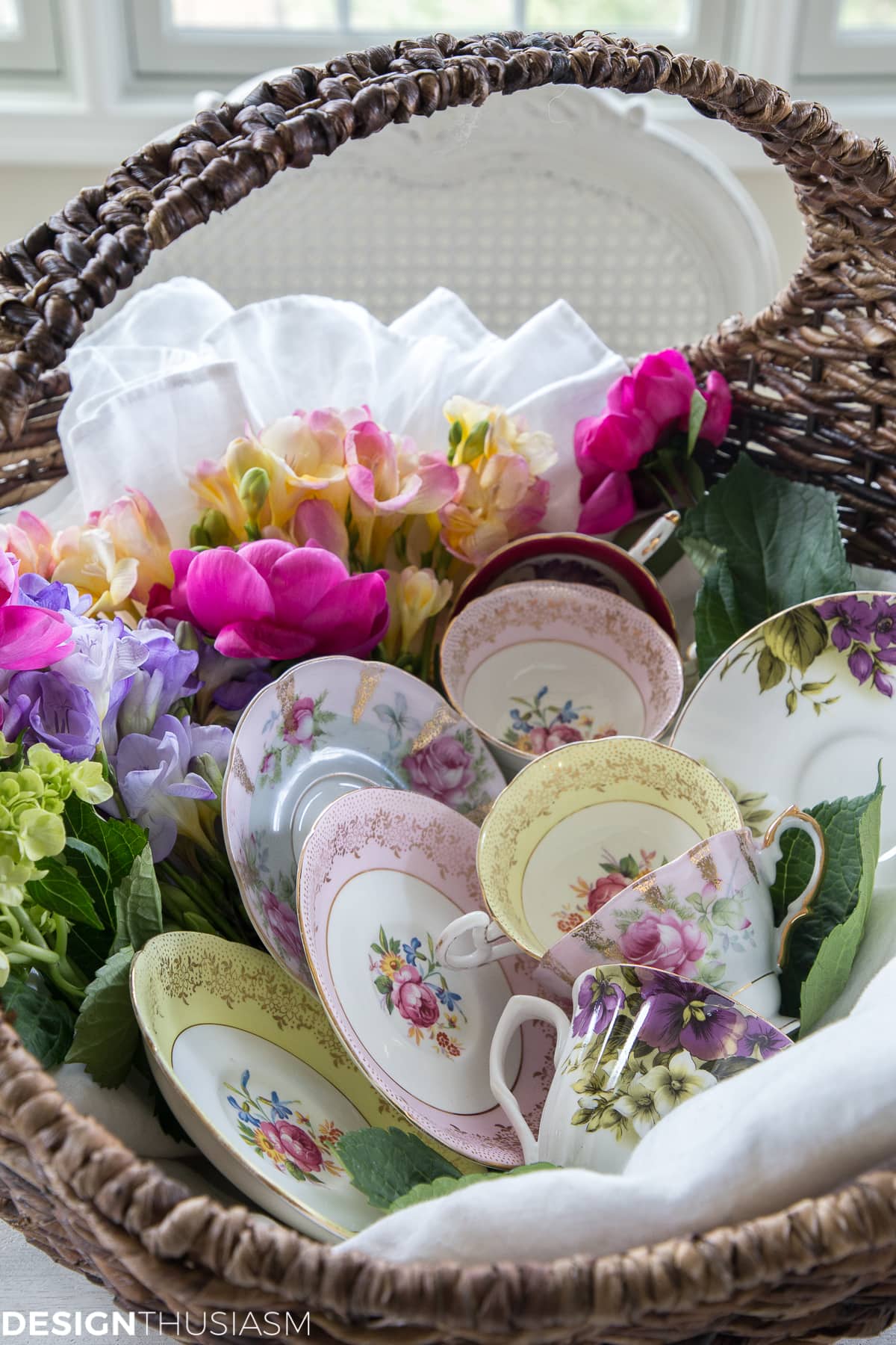 vintage teacups and saucers displayed in a basket with flowers