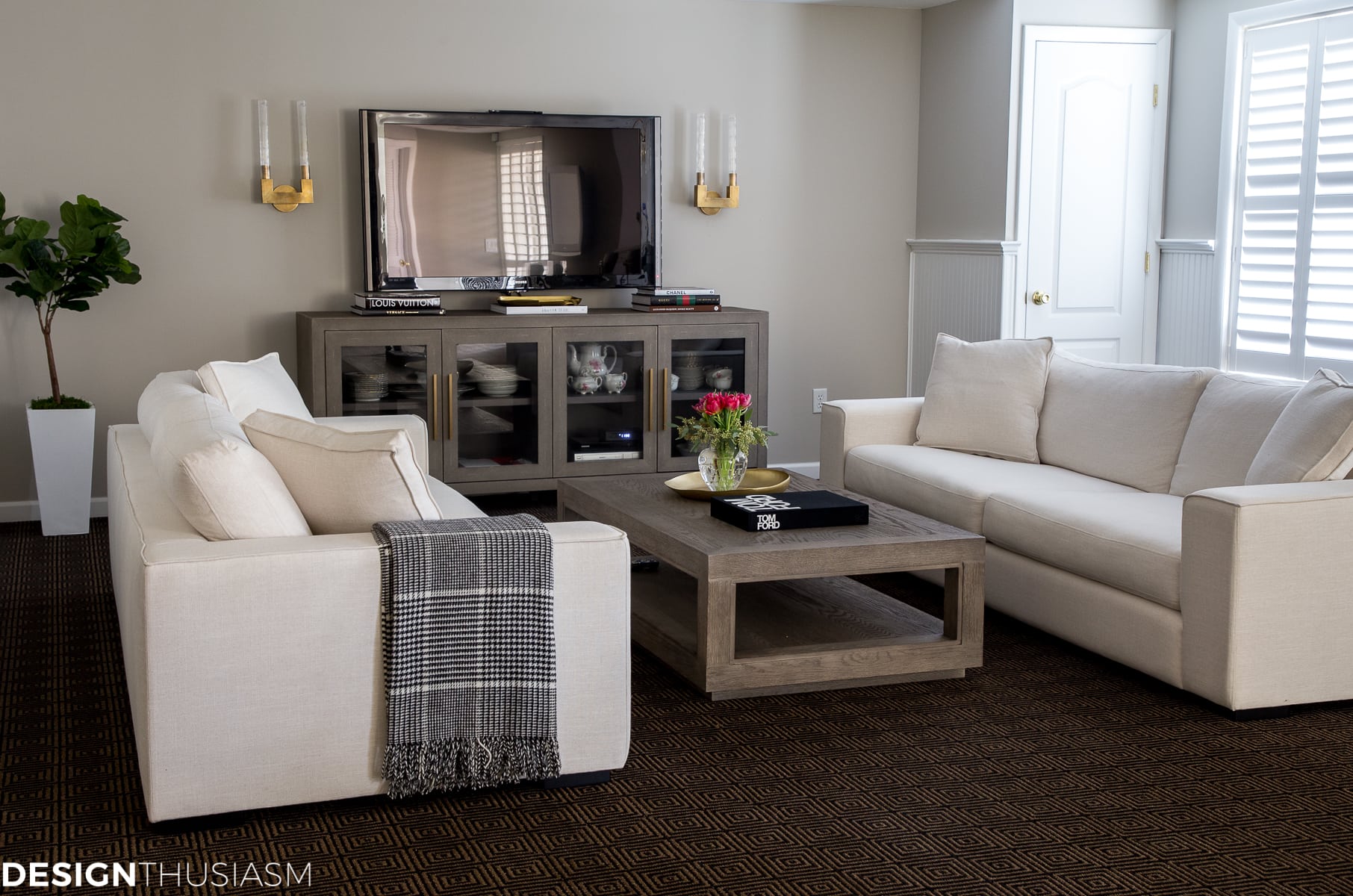 basement finishing couches and TV with plantation shutters on windows