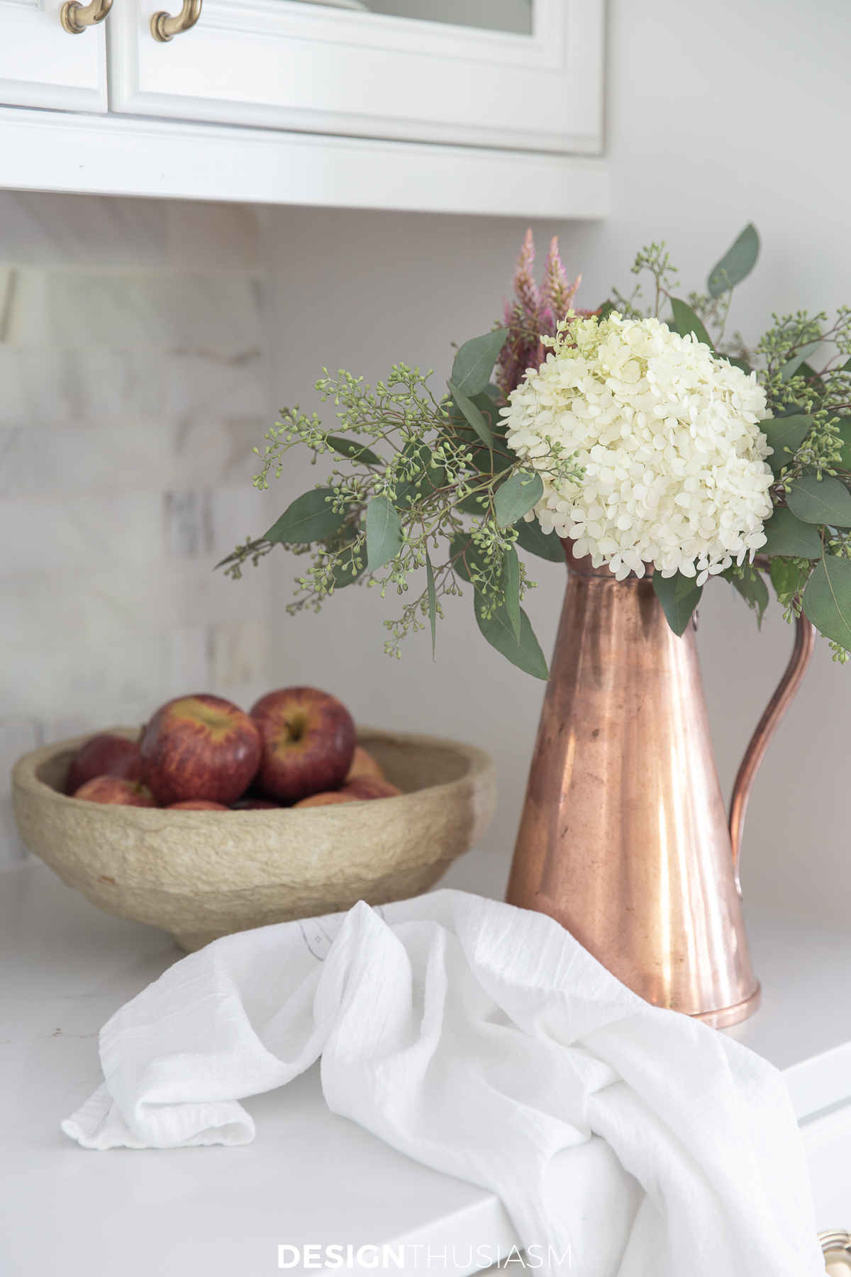 apples in a bowl and copper pitcher