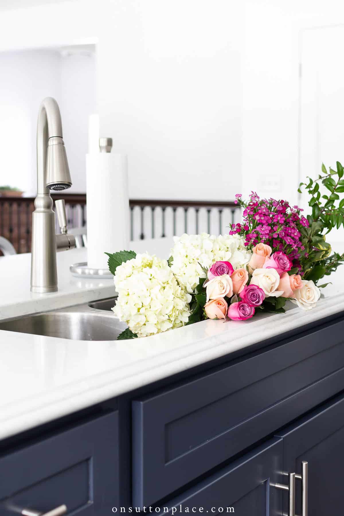 blue and white kitchen with flowers in sink
