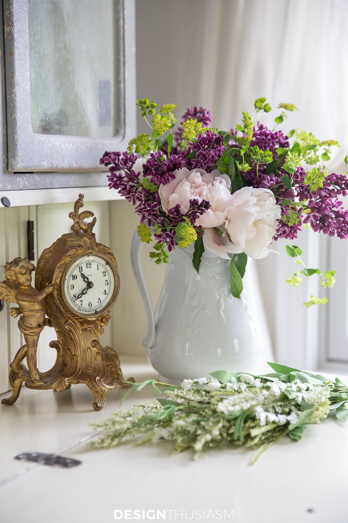 peonies and a french clock on a desk