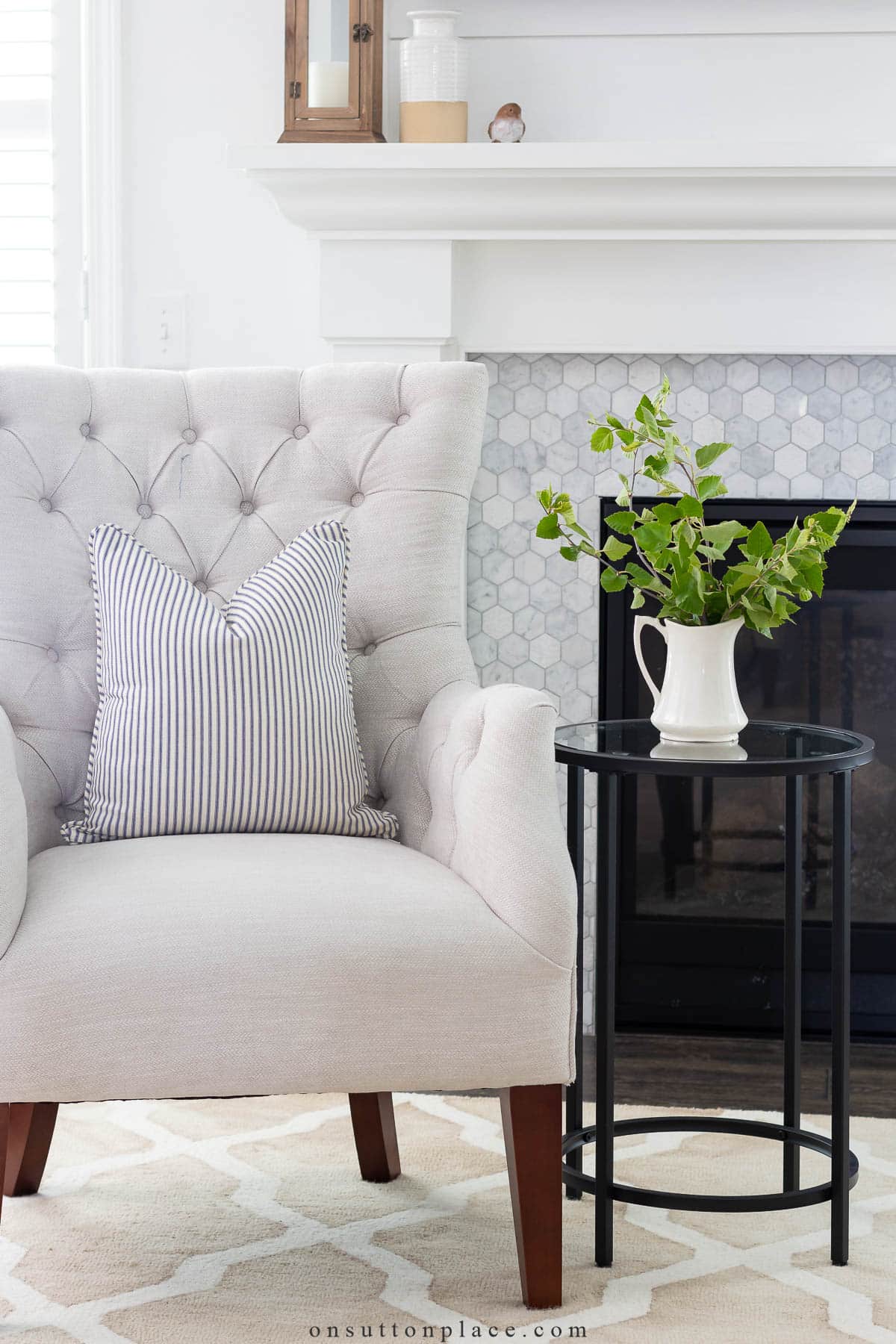 blue ticking pillow on tufted chair in front of fireplace