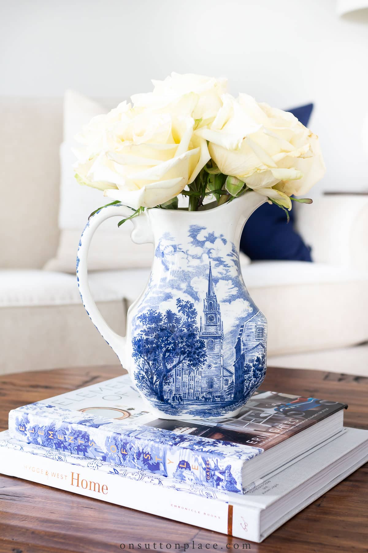 books on coffee table with pitcher of flowers