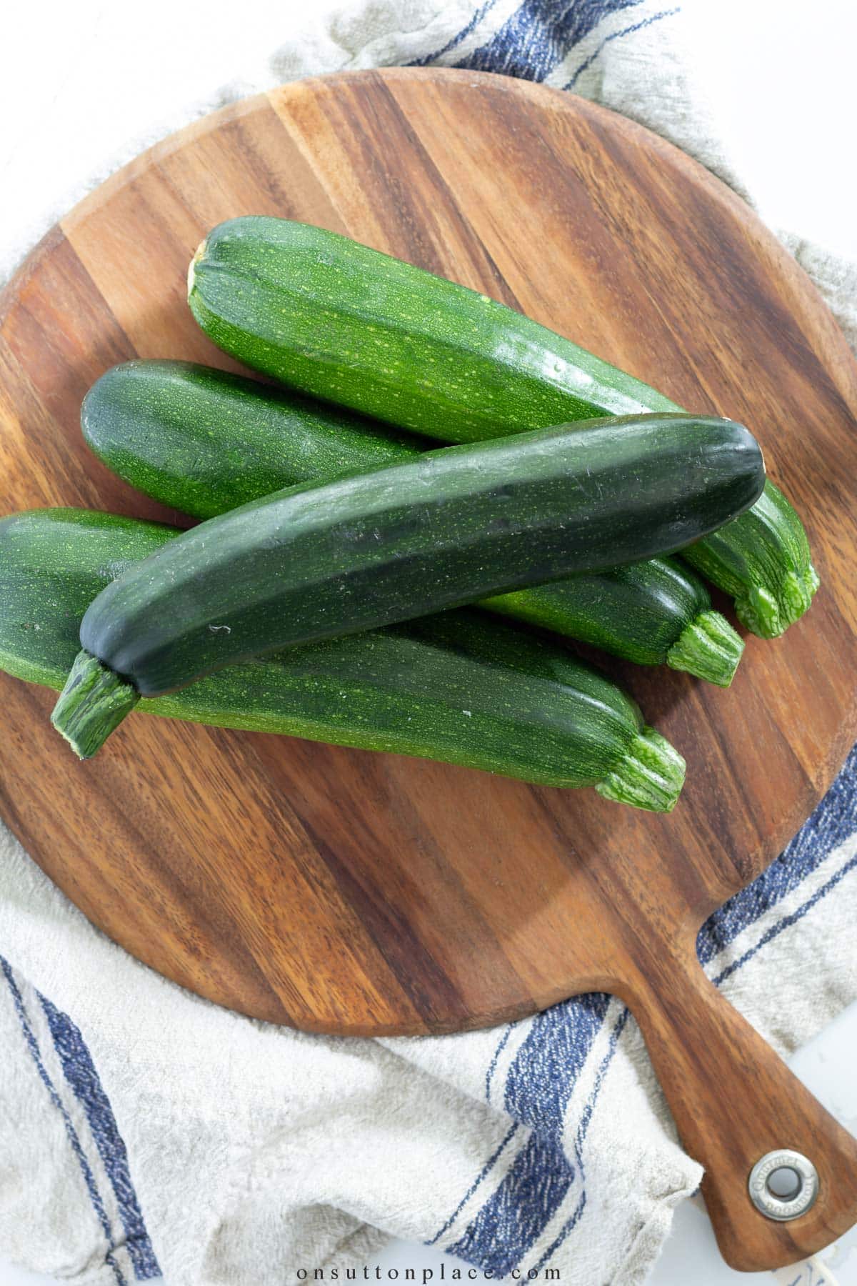 4 zucchini squash on round wood board