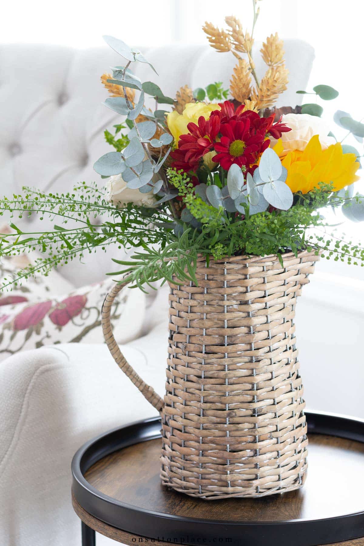 wicker pitcher with fall flowers tufted chair with colorful pillow
