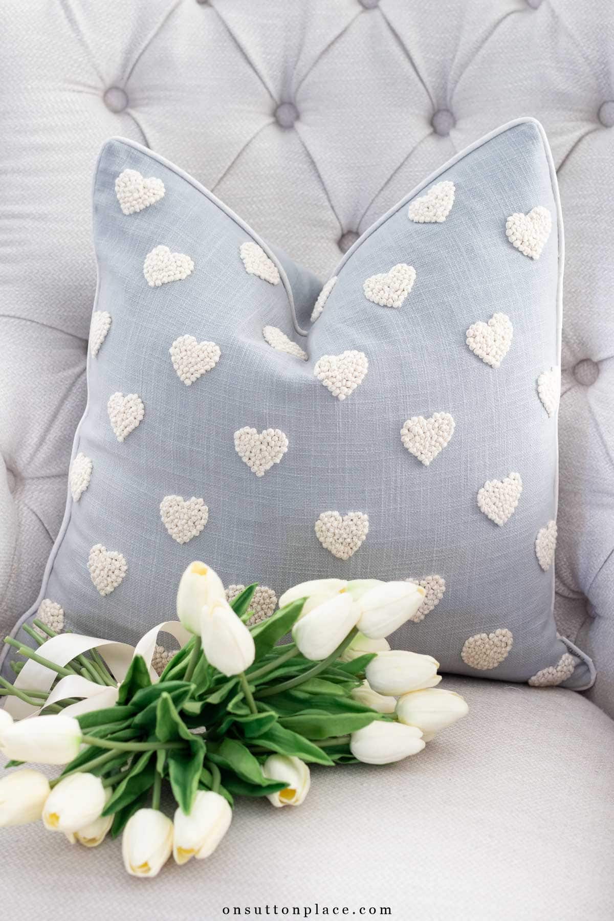 blue pillow with embroidered hearts on chair with tulips