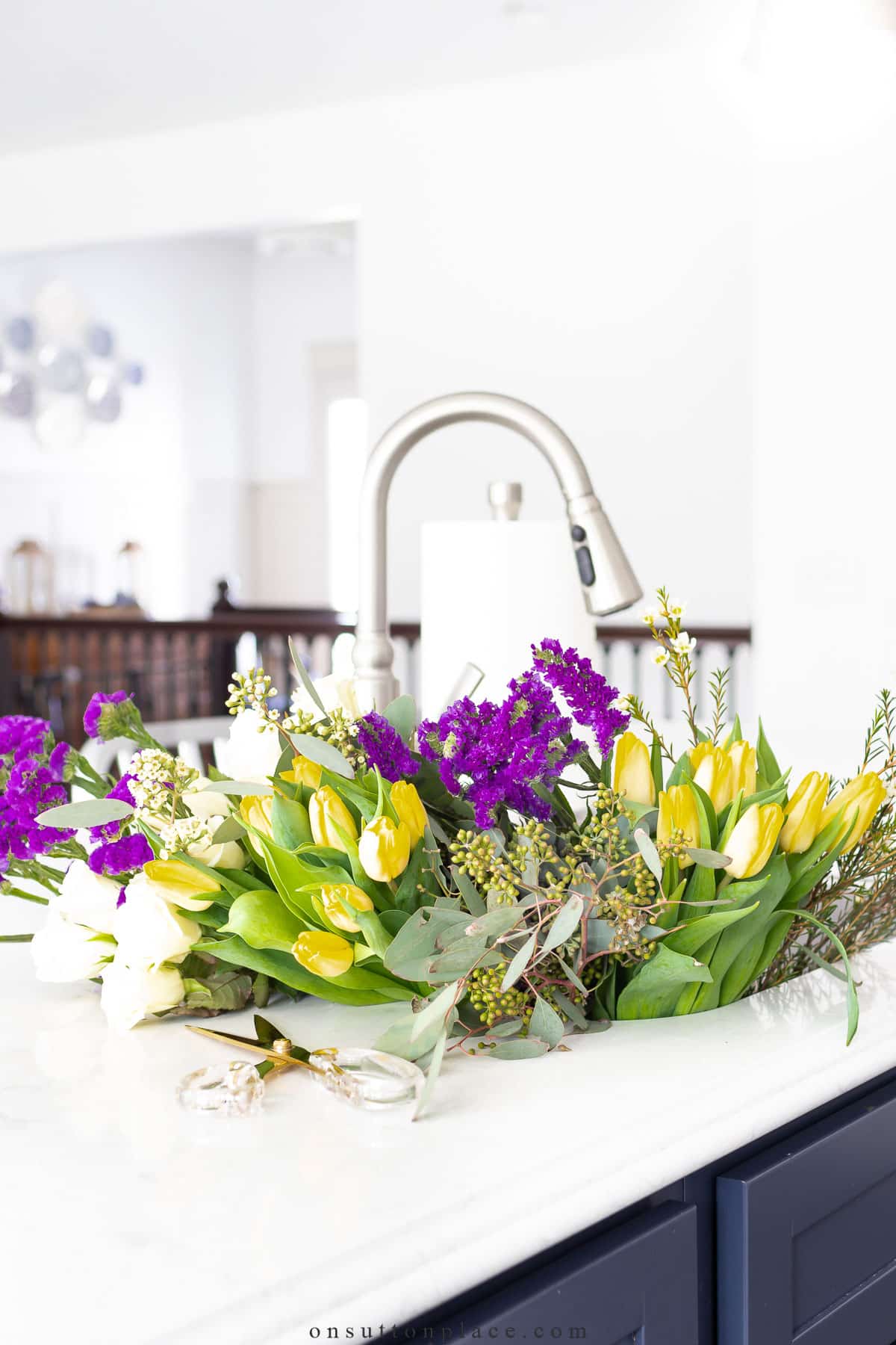 yellow tulips and seeded eucalyptus in kitchen sink