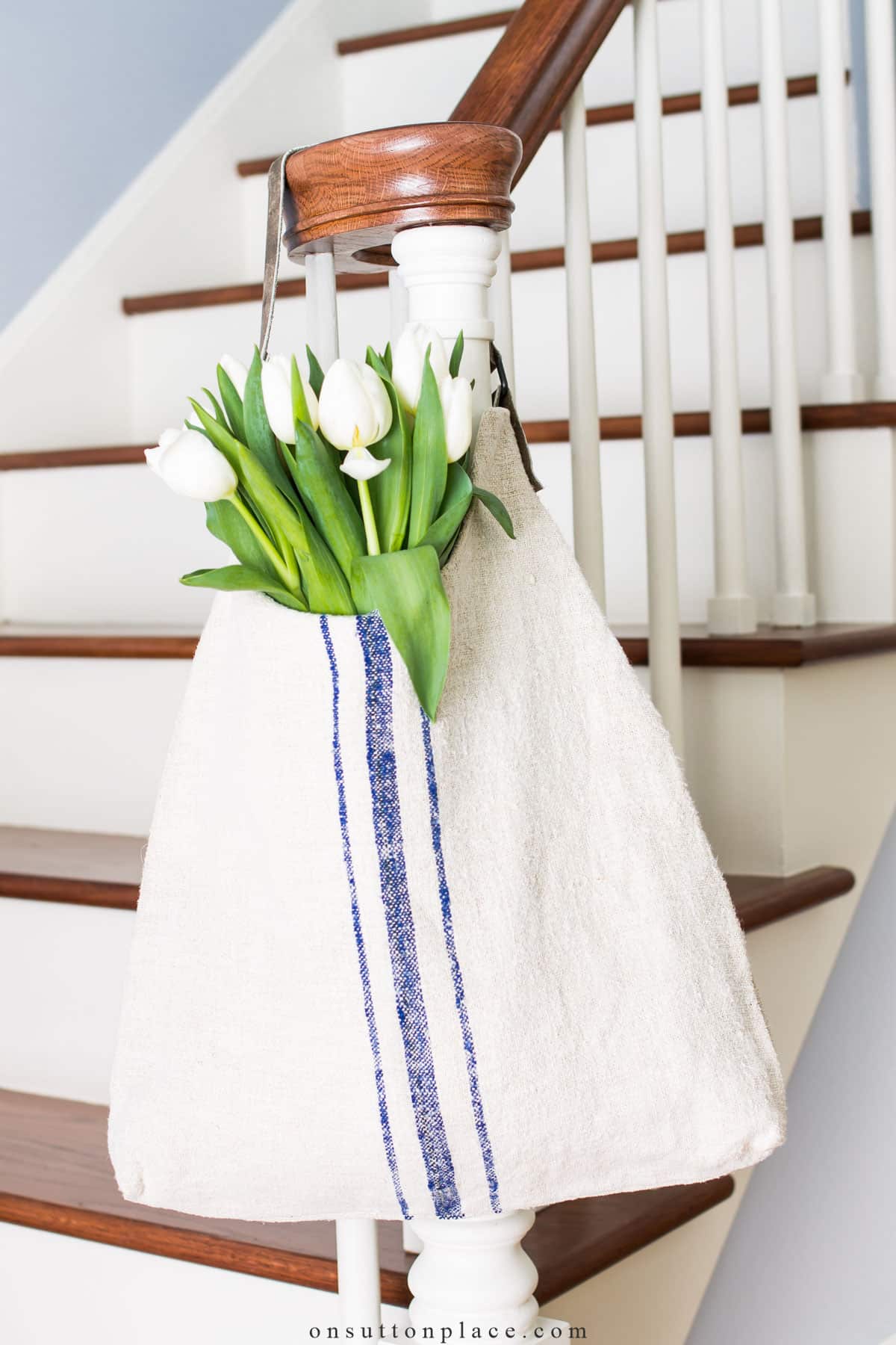 antique grain sack tote bag on stairway banister with tulips